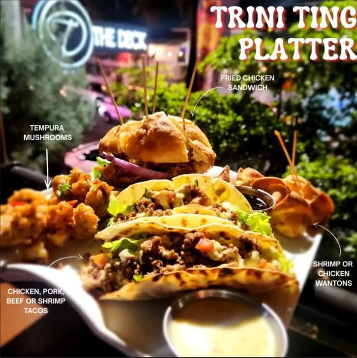 Trini Ting Platter — fried chicken sandwich, tacos, tempura mushrooms and wontons, shot against the Avenue at night